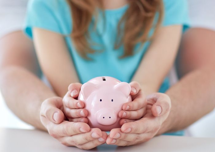 Ein Erwachsener und ein Kind halten ein Sparschwein in den Händen